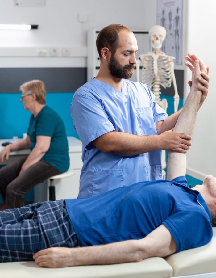 Chiroptractor doing osteopathic massage on aged patient for hand muscle recovery. Nurse giving assistance to stretch arm joint of senior man for osteopathy treatment and healthcare.